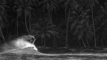John Barton lokasi Pulau Mentawai. Kepulauan Mentawai adalah rumah bagi beberapa gelombang terbaik di planet ini. Ini juga merupakan rumah bagi pemandangan yang menakjubkan di mana hutan memperebutkan real estat hingga ke tepi laut, kata Barton. Bagi para peselancar, titik ini adalah di mana kita secara obsesif menghabiskan sebagian besar waktu kita (atau ingin). Untuk mendokumentasikan keindahan penuh dari adegan-adegan ini, saya sering menarik kembali panjang fokus, mengundang pemirsa untuk mengalami keagungan penuh zona pesisir ini sambil secara bersamaan menangkap aksi kecepatan tinggi dari olahraga yang saya sukai. Saya memotret yang ini dalam warna hitam dan putih untuk menekankan kontras elemen saat matahari menerangi subjek sementara latar belakang berada dalam bayangan. Foto: Ocean Photographer Awards