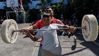 Seorang atlet (berbaju merah) sedang mengajarkan teknik dasar angkat beban kepada siswa di SMP Petra Malang, Jawa Timur, Indonesia, pada 15 Agustus 2024.  