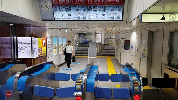 Seorang staf kereta api berjalan menuju pintu putar yang ditutup saat layanan kereta peluru 