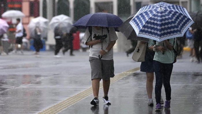 Topan Ampil yang disertai hujan mendekati wilayah Tokyo, Jepang. Angin topan tersebut membuat warga kewalahan saat berada di luar rumah.