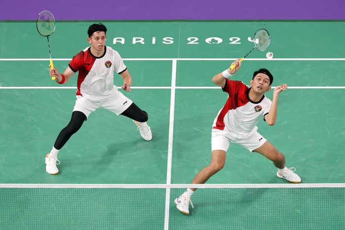 PARIS, FRANCE - AUGUST 01: Fajar Alfian and Muhammad Rian Ardianto of Team Indonesia play a shot during the mens doubles badminton quarter-final match against Team China on day six of the Olympic Games Paris 2024 at Porte de La Chapelle Arena on August 01, 2024 in Paris, France. (Photo by Michael Reaves/Getty Images)