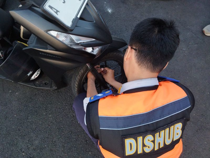 Dishub gembosi motor parkir sembarangan di seberang Istana Merdeka, Jakarta Pusat, 17 Agustus 2024. (Kurniawan Fadilah/detikcom)