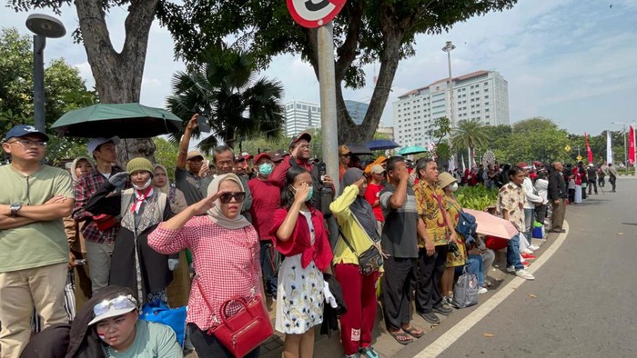 Pengibaran bendera Merah Putih berlangsung di Istana Merdeka, Jakarta, memperingati HUT ke-79 RI. Momen ini turut diikuti masyarakat yang hadir di area depan Istana Merdeka dengan melakukan sikap hormat.