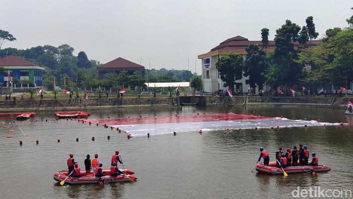 Relawan se-Provinsi Banten membentangkan bendera merah putih sebesar 1.200 meter persegi di danau dalam rangka HUT ke-79 RI (Bahtiar/detikcom)