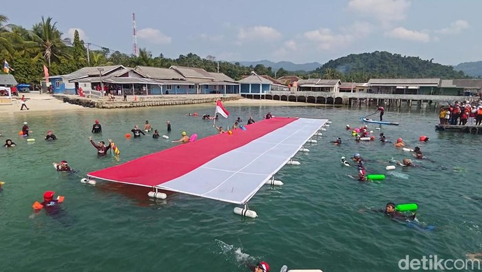 Sejumlah perenang membuat rekor berenang sejauh 8,3 km sambil membawa bendera raksasa