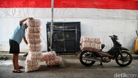 Seorang pedagang yang sedang merapihkan barang dagangannya itu pun dipotret dengan latar belakang bendera merah putih besar yang membentang di dinding.