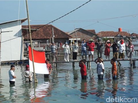Warga Dukuh Timbulsloko, Kecamatan Sayung, Kabupaten Demak, menggelar upacara HUT ke-79 RI di permukiman mereka yang terendam rob, Sabtu (17/8/2024).