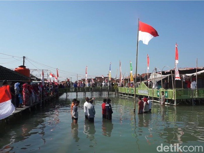 Warga Dukuh Timbulsloko, Kecamatan Sayung, Kabupaten Demak, menggelar upacara HUT ke-79 RI di permukiman mereka yang terendam rob, Sabtu (17/8/2024).