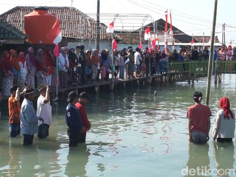 Warga Dukuh Timbulsloko, Kecamatan Sayung, Kabupaten Demak, menggelar upacara HUT ke-79 RI di permukiman mereka yang terendam rob, Sabtu (17/8/2024).