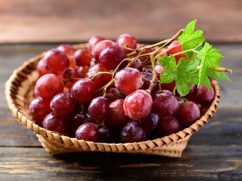 Fresh red grapes fruit in a basket on wooden background