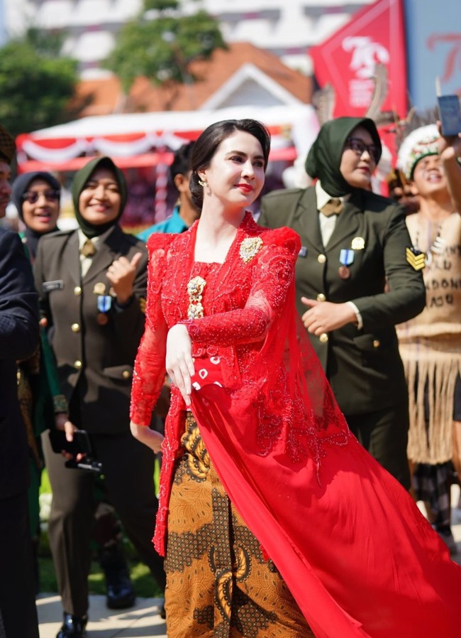 Kebaya rancangan desainer Diana M Putri itu tampak memiliki kain seperti jubah pada bagian belakangnya. Atasan kebaya merah itu kemudian dipadukan dengan bawahan kain batik coklat. Foto: Instagram/@arumibachsin_94