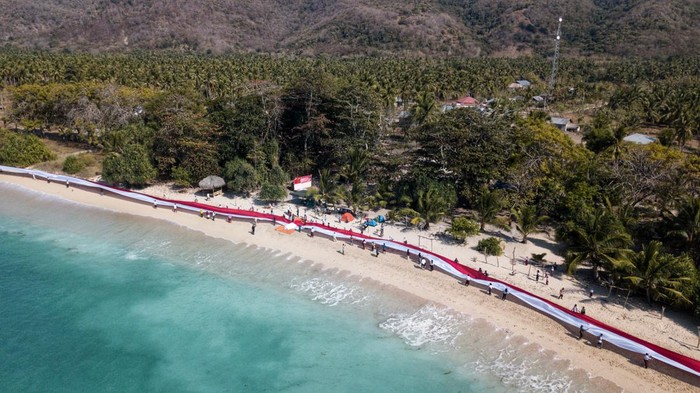 Ratusan warga Desa Wowong, Kecamatan Omesuri, Kabupaten Lembata, NTT, membentangkan bendera merah putih sepanjang satu kilometer, dalam rangka memeriahkan Hari Ulang Tahun (HUT) Ke-79 Republik Indonesia, di bibir Pantai Nusantara, Nusa Tenggara Timur.