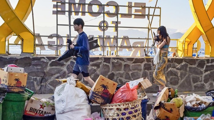Tumpukan Sampah Mencoreng Keindahan Gili Trawangan Dua wisatawan asing melintas dekat tumpukan sampah di destinasi wisata Gili Trawangan, Desa Gili Indah, Kecamatan Pemenang, Tanjung, Lombok Utara, NTB, Minggu (18/8/2024). Menurut data Dinas Lingkungan Hidup Kabupaten Lombok Utara, tingkat produksi sampah yang dihasilkan dari kegiatan jasa usaha wisata serta masyarakat di Gili Trawangan mencapai 7 - 8 ton perhari dan jumlahnya melonjak hingga 16 ton per hari pada musim liburan. ANTARA FOTO/Ahmad Subaidi/Spt.