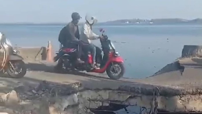 Pengendara melintasi jalan yang hampir ambruk di Parepare.