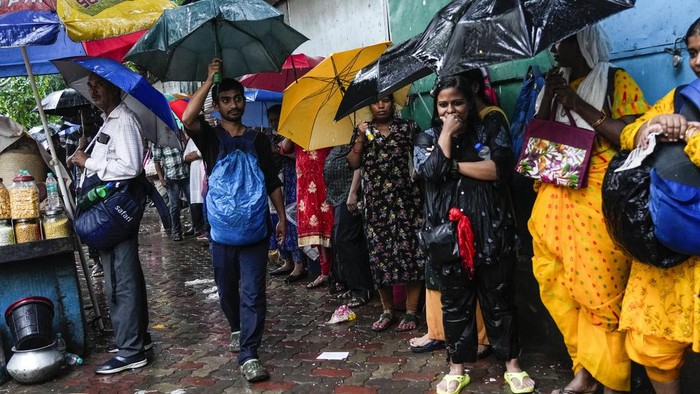 Terjebak Hujan, Pekerja India Neduh di Toko yang Tutup Hujan monsun mengguyur wilayah Kolkata, India. Para pekerja yang terjebak hujan, meneduh di depak toko yang sedang tutup.