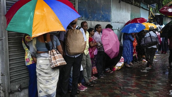 Terjebak Hujan, Pekerja India Neduh di Toko yang Tutup Hujan monsun mengguyur wilayah Kolkata, India. Para pekerja yang terjebak hujan, meneduh di depak toko yang sedang tutup.