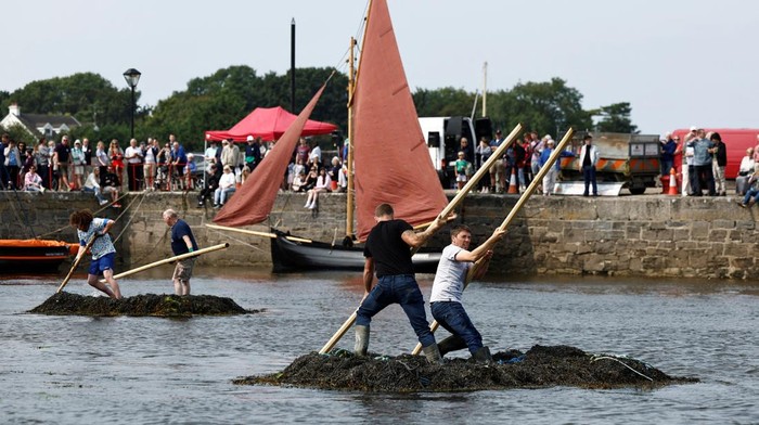 A team of seaweed racers pushes their three tonne seaweed bundles tied together, known as 'Climin', with a long pole in the sea during an annual seaweed race at the Cruinniu na mBad (gathering of the boats) regatta in Kinvara, Ireland August 18, 2024. REUTERS/Clodagh Kilcoyne