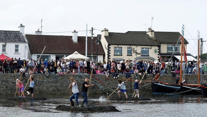 A team of seaweed racers pushes their three tonne seaweed bundles tied together, known as 'Climin', with a long pole in the sea during an annual seaweed race at the Cruinniu na mBad (gathering of the boats) regatta in Kinvara, Ireland August 18, 2024. REUTERS/Clodagh Kilcoyne