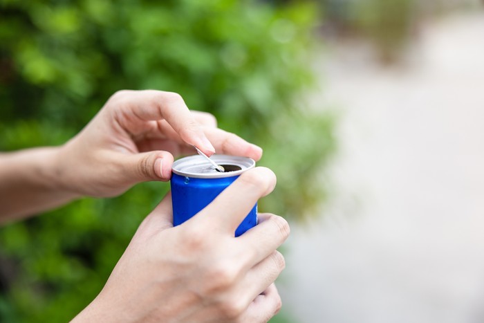 Closeup woman hand open cola can with nature background