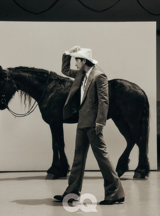Dalam foto lain, Gong Yoo berpose dengan kuda sungguhan. Dia tampil manly memegang koleksi Palm Tree Material Cowboy Silhouette Lasso Hat seharga 1,9 juta won atau Rp 22 juta. Foto: dok. GQ Korea