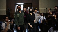 Helena tampak mengenakan baju dan celana hitam saat masuk ke ruang sidang. Helena juga mengenakan masker berwarna hitam.  