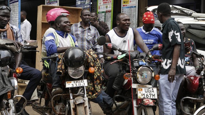 Drivers of motorcycle taxis, known locally as boda-bodas, ride with passengers on a street of Kampala, Uganda, on July 18, 2024. (AP Photo/Hajarah Nalwadda )