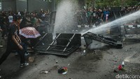 Polisi pun menembakkan meriam air untuk mendorong mundur massa aksi. Sejumlah massa ada yang terjatuh akibat tembakan meriam air tersebut.
