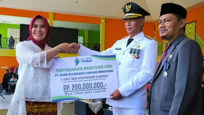 Pimpinan Bank Sulselbar Cabang Enrekang, Hasdiana menyerahkan bantuan secara simbolis dan diterima oleh Pj Bupati Enrekang, H Baba di Lapangan Abubakar Lambogo Enrekang.