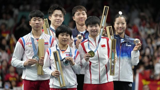 Ri Jong Sik dari Korea Utara, kiri, dan Kim Kum, latar depan kiri, dengan medali perunggu mereka, Wang Chuqin dari China, latar belakang kiri, dan Sun Yingsha, latar depan kanan, dengan medali emas mereka, Shin Yubin dari Korea Selatan, kanan, dan Lim Jonghoon dengan medali perunggu mereka berpose untuk para fotografer selama upacara penyerahan medali di Olimpiade Musim Panas 2024, Selasa, 30 Juli 2024, di Paris, Prancis. (AP Photo/Petros Giannakouris)