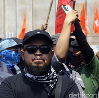 Rigen mengandalkan kaus hitam dan topi senada, dengan scarf monokrom. (Foto: Ari Saputra/detikcom)