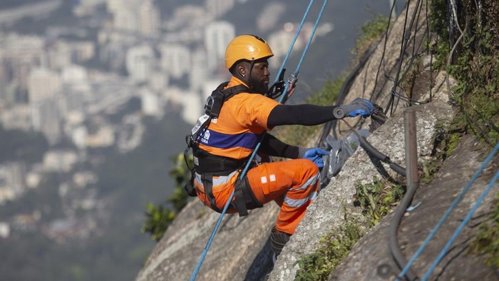 Trash collectors rappel down Corcovado Mountain to remove garbage dumped on the slope of the Christ the Redeemer Statue in Rio de Janeiro, Thursday, Aug. 22, 2024. (AP Photo/Bruna Prado)