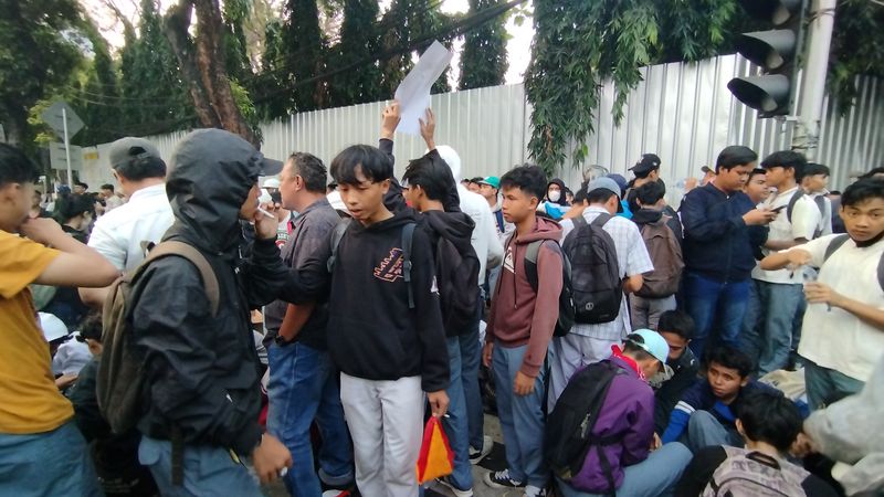 Massa yang mengenakan celana abu-abu mendatangi kantor KPU sambil membawa bambu