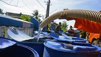 Petugas mengisi air ke dalam wadah saat penyaluran bantuan air bersih di Desa Pajukukang, Kecamatan Bontoa, Kabupaten Maros, Sulawesi Selatan, Jumat (23/8/2024).  