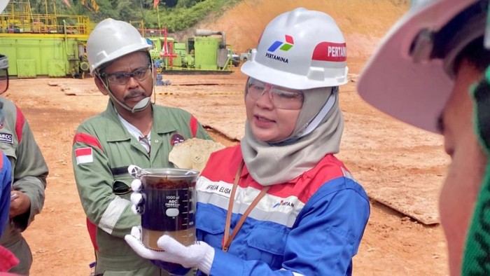Afrilia Elisa, Sr Petroleum Engineer PHR, Kepala Proyek VENUS, tengah menunjukkan bejana berisi fluida lapisan minyak hasil dari sumur evaluasi menggunakan VENUS. (dok. Istimewa)