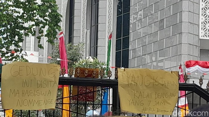 Poster bertuliskan Tolak Dinasti Politik dan Gedung Ini Disita Mahasiswa Nommensen terpasang di gerbang kantor DPRD Sumut saat terjadi aksi unjuk rasa mahasiswa. (Nizar Aldi/detikSumut)