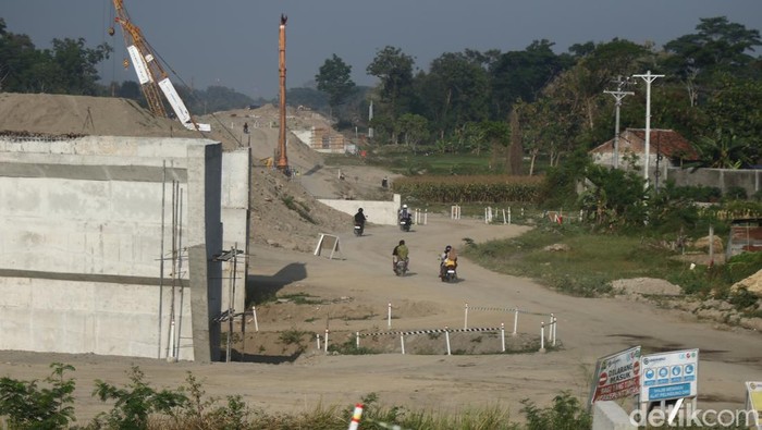 Warga melintas di area konstruksi tol Jogja-Solo di Purwomartani, Kalasan, Sleman, Sabtu (24/8/2024).