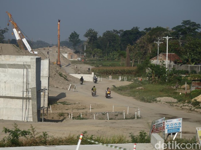 Warga melintas di area konstruksi tol Jogja-Solo di Purwomartani, Kalasan, Sleman, Sabtu (24/8/2024).