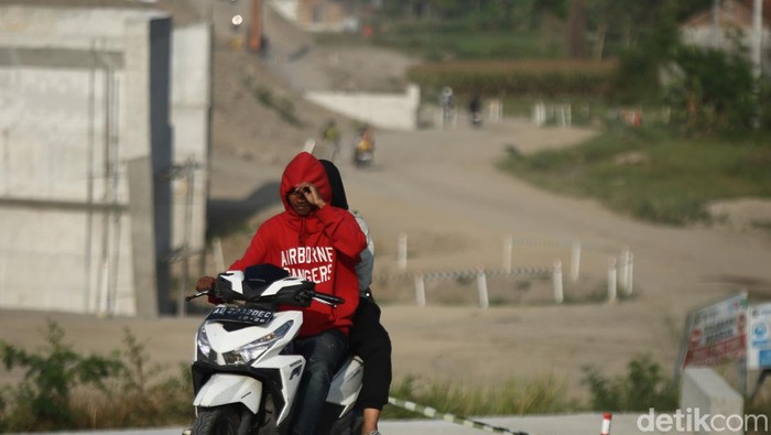 Warga melintas di area konstruksi tol Jogja-Solo di Purwomartani, Kalasan, Sleman, Sabtu (24/8/2024).