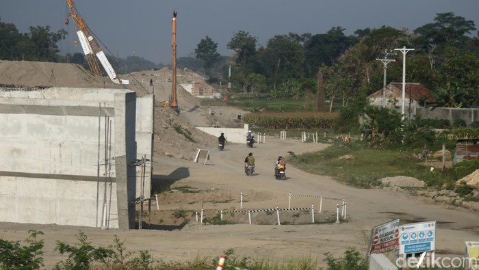 Warga melintas di area konstruksi tol Jogja-Solo di Purwomartani, Kalasan, Sleman, Sabtu (24/8/2024).