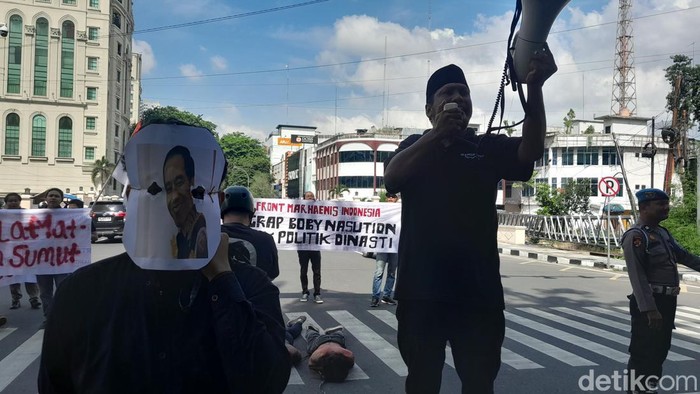 Massa berdemonstrasi di depan Kantor Wali Kota Medan dengan membawa poster Bobby Nasution bersalaman dengan AGK. (Nizar Aldi/detikSumut)