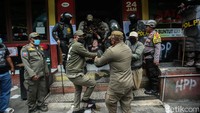Pemilik warung makan Mas Arofiq dibawa petugas saat menolak bangunannya dibongkar di Kawasan Puncak, Bogor, Senin (26/8/2024).  