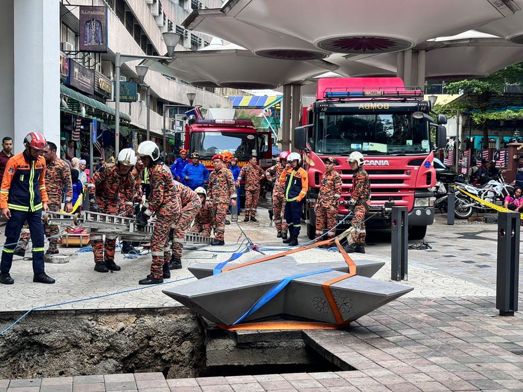 Pemadam Kebakaran dan Penyelamatan Malaysia ini menunjukkan petugas penyelamat memasuki lubang pembuangan yang dalam setelah menerima laporan bahwa seorang wanita terjatuh ke dalam lubang pembuangan setelah satu bagian trotoar ambruk di Kuala Lumpur, Jumat, 23 Agustus 2024. (AP Photo/Vincent Thian)