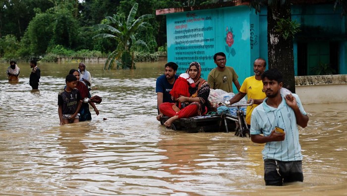 Penampakan Banjir Parah Rendam Bangladesh People move a cart with a woman and a child through a flooded street, amid severe flooding in the Fazilpur area of Feni, Bangladesh, August 26, 2024. REUTERS/Mohammad Ponir Hossain