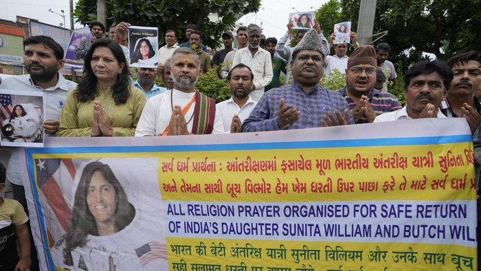 A child holds a poster of Sunita Williams as others pray during the all religion prayer for the safe return of American astronaut of Indian origin Sunita Williams and Butch Wilmore from the International Space Station (ISS), in Ahmedabad, India, Sunday, Aug. 25, 2024. (AP Photo/Ajit Solanki)