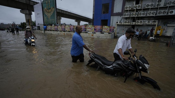 Girls push an auto riksha through a flooded road during heavy rain in Ahmedabad, India, Monday, Aug. 26, 2024. (AP Photo/Ajit Solanki)
