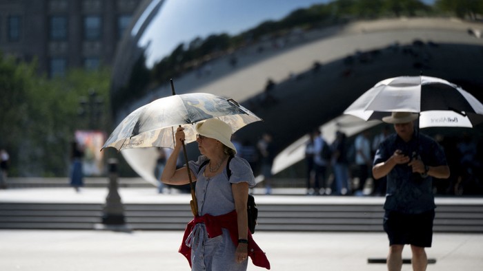 A woman uses an umbrella to shield herself from the sun during a period of hot weather in Chicago, Illinois, U.S. August 26, 2024. REUTERS/Vincent Alban