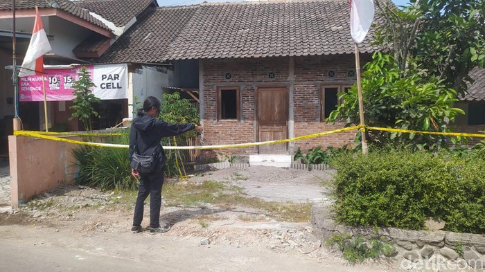 Petugas memasang garis polisi di rumah yang diduga untuk mengoplos miras di Paremono, Mungkid, Magelang, Selasa (27/8/2024).