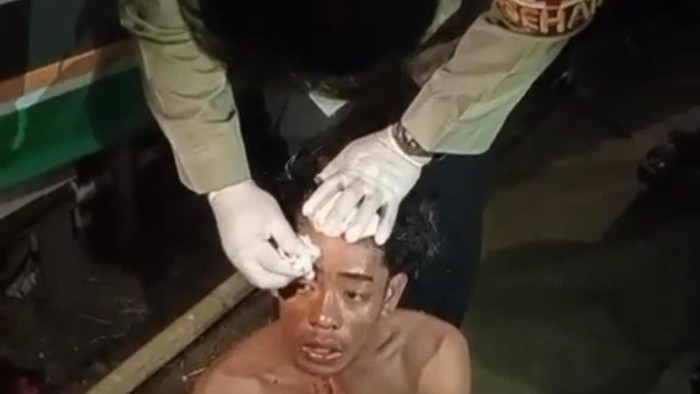 Polisi mengobati pendemo bayaran di Makassar yang terluka di kepalanya.