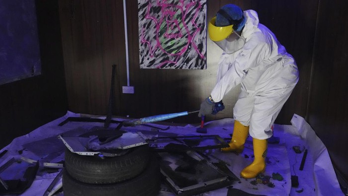 Olaribigbe Akeem, wearing protective gear, uses a sledgehammer to break a television set to vent his anger inside the Shadow Rage Room in Lagos, Nigeria, Sunday, July 28, 2024. (AP Photo/Sunday Alamba)