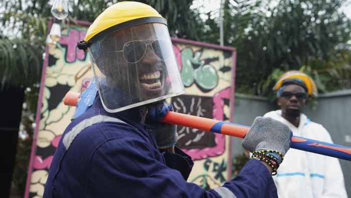 Olaribigbe Akeem, wearing protective gear, uses a sledgehammer to break a television set to vent his anger inside the Shadow Rage Room in Lagos, Nigeria, Sunday, July 28, 2024. (AP Photo/Sunday Alamba)